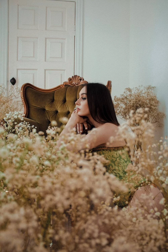 Femme posant dans un salon rempli de fleurs au sein d'un corset vert