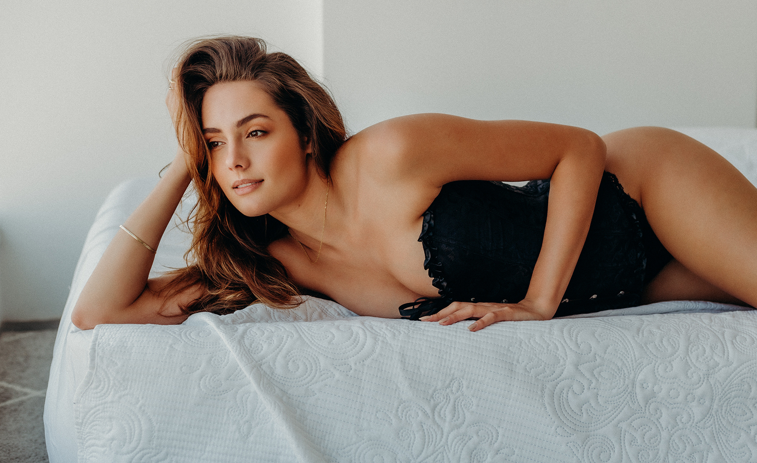 Femme allongée sur un lit portant un corset bustier noir